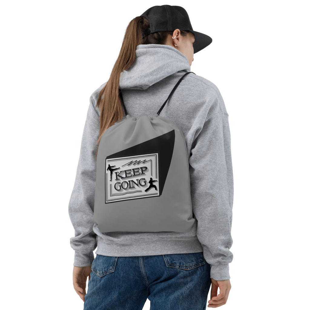 Back of girl in grey sweatshirt wearing black cap with a Keep Going drawstring bag on back.
