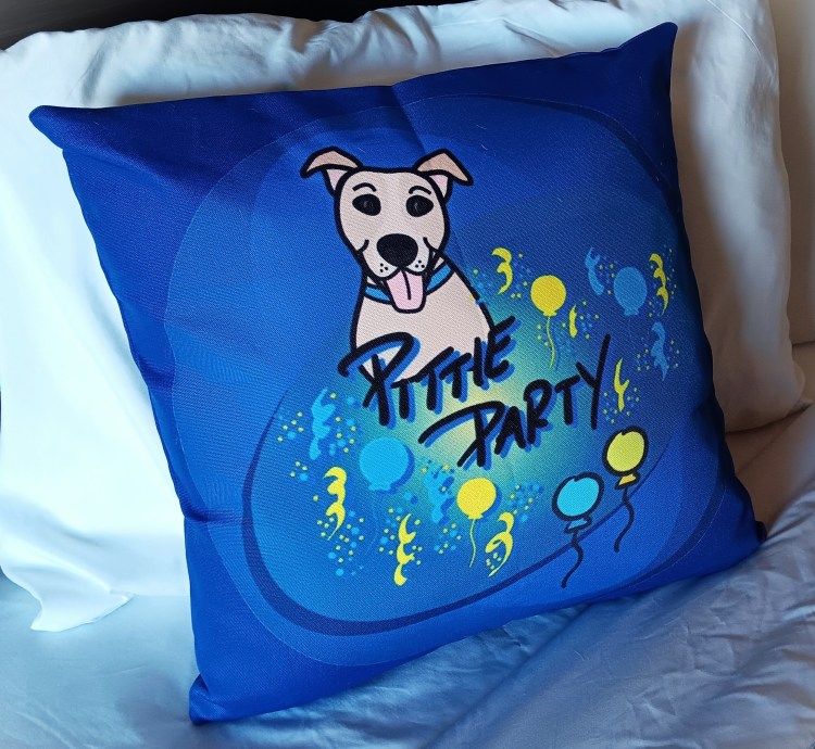 Deep blue Pittie Party pillow on bed with white pillows